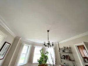 Newly painted interior ceiling and crown molding in a dining room, showcasing a clean, professional finish.
