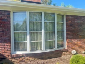 Malone Painting crew painting exterior trim on a red brick ranch-style home in St. Louis, enhancing curb appeal with fresh white finishes.