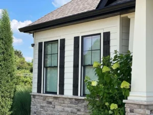 St. Louis home exterior with freshly painted white siding, black shutters, and stone accents, beautifully finished by Malone Painting.