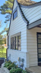 Exterior painting project on a two-story home, showcasing freshly painted white brick and siding with dark window trim.