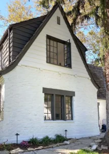 Exterior painting project on a two-story home, showcasing freshly painted white brick and siding with dark window trim.