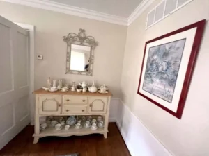 Finished interior painting project in a hallway, showcasing freshly painted beige walls with clean white wainscoting and trim.