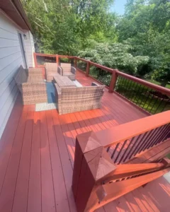 Finished residential deck refinishing project, showing a newly stained dark brown deck and railings with outdoor furniture.
