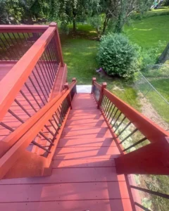 Finished residential deck refinishing project, showing a newly stained dark brown deck and railings with outdoor furniture.