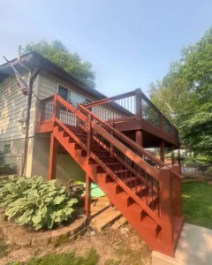 Finished residential deck refinishing project, showing a newly stained dark brown deck and railings with outdoor furniture.