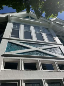 Freshly painted St. Louis Tudor-style home exterior featuring crisp white trim and bold teal accent by Malone Painting. Professional exterior painting enhances curb appeal, highlights architectural details, and protects historic homes from weather damage.