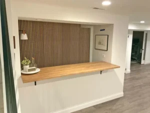 Modern finished basement in St. Louis featuring freshly painted white walls, wood bar counter, and accent slat wall, updated by Malone Painting interior services.