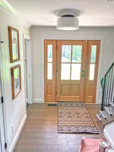 Bright St. Louis entryway with freshly painted white walls, natural wood front door, and modern trim, completed by Malone Painting interior painting experts.