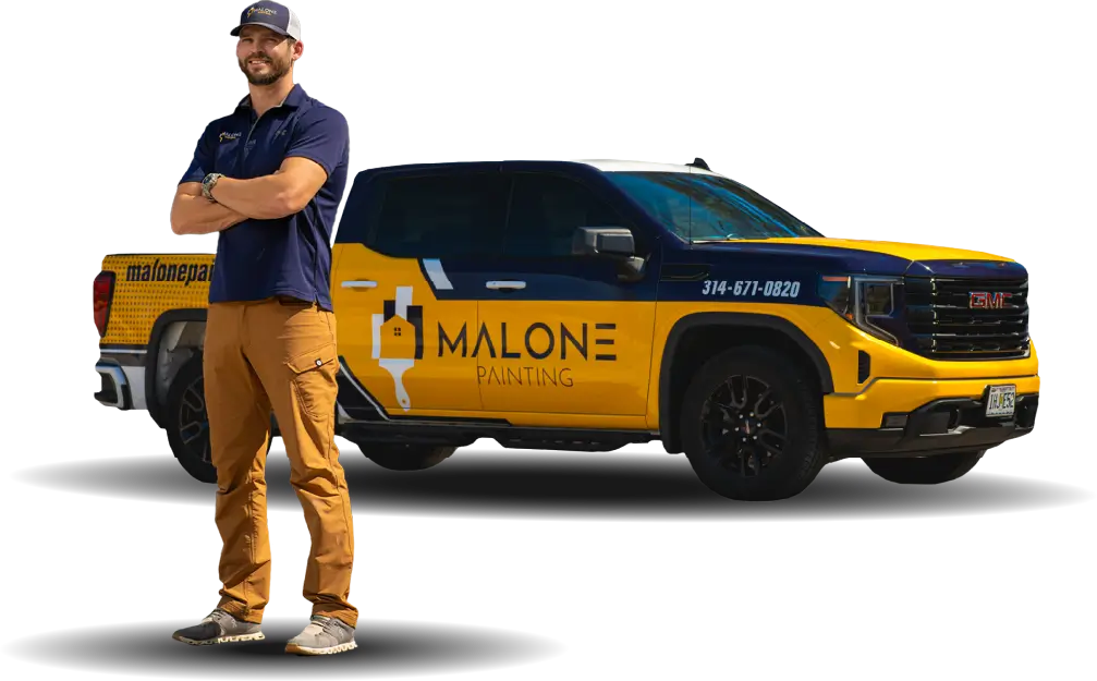 A man named Jon, a production manager of Malone Painting, wearing a Malone Painting uniform and a yellow cap stands with his arms crossed next to a branded yellow and blue Malone Painting truck. The background is transparent.