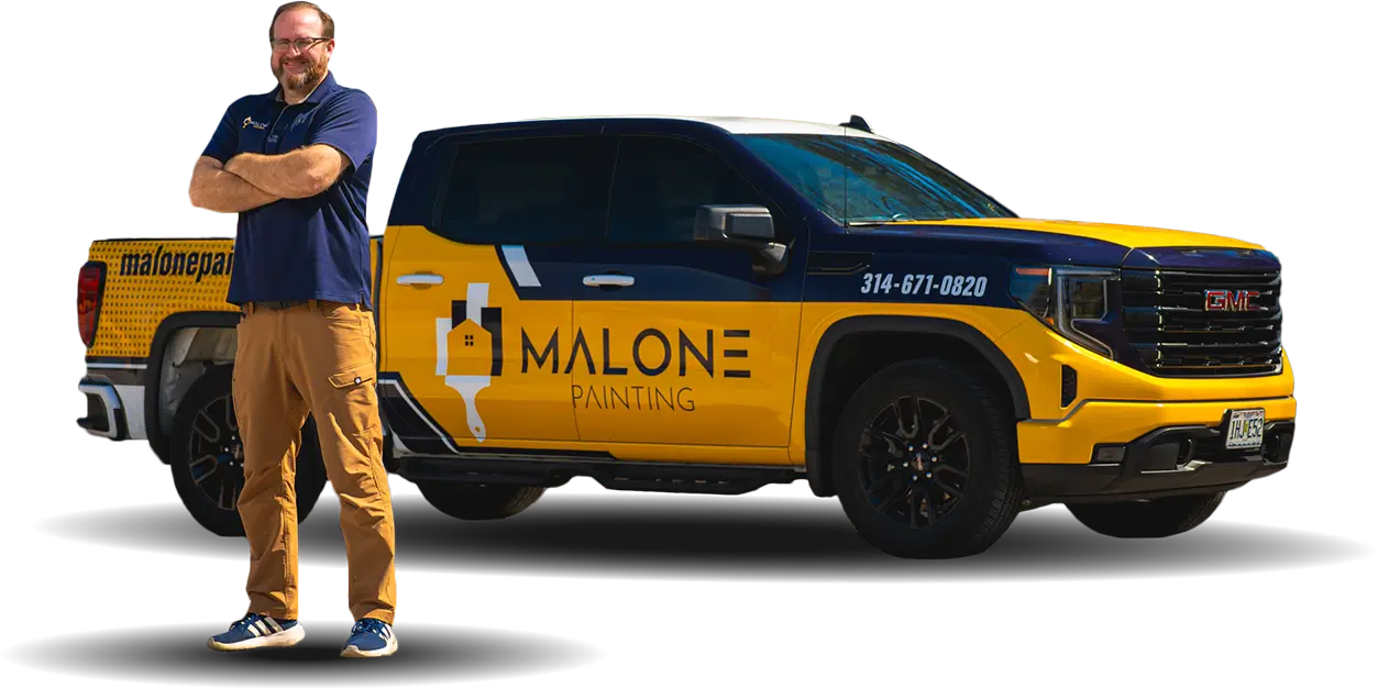 Jack, one of the Production Managers at Malone Painting, stands with his arms crossed next to a branded yellow and blue company truck. The background is transparent